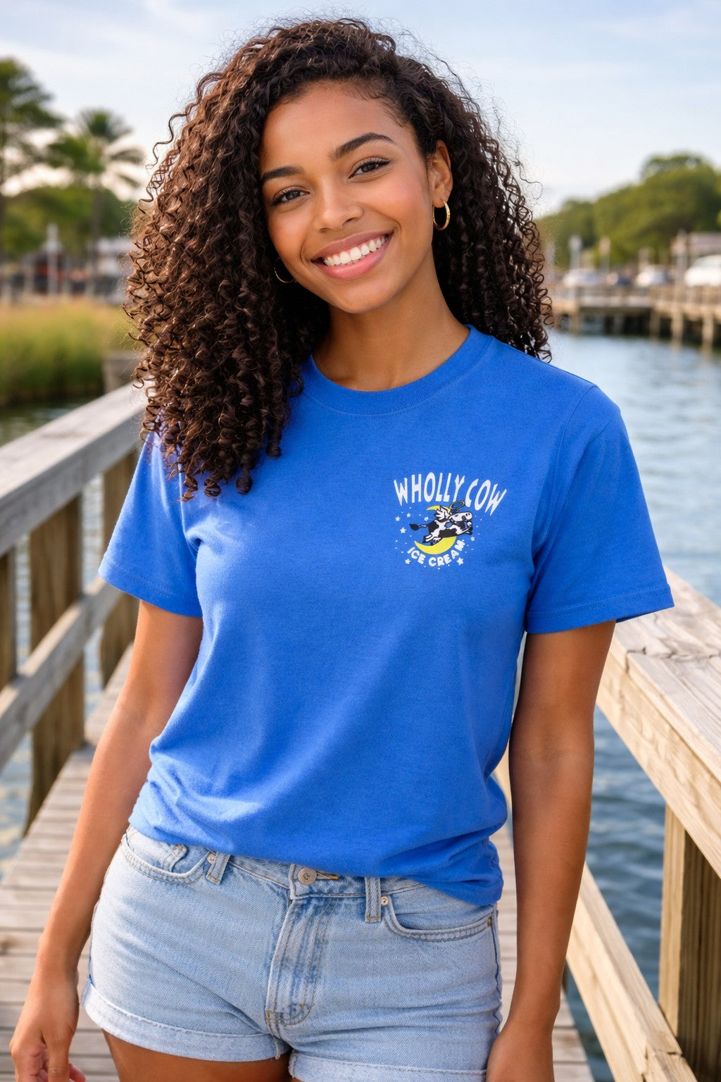 Woman wearing a blue t-shirt with 'Wholly Cow' ice cream logo by a Shem Creek Mount Pleasant waterfront Charleston, South Carolina