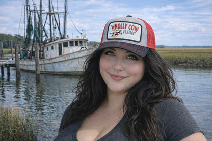 Woman wearing a 'Wholly Cow' Richardson trucker snapback baseball hat with a local Lowcountry shrimp fishing boat in the background